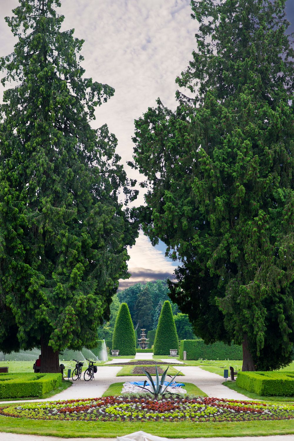 Explore a beautifully symmetrical park pathway surrounded by lush greenery and towering trees in Lednice, Czech Republic.