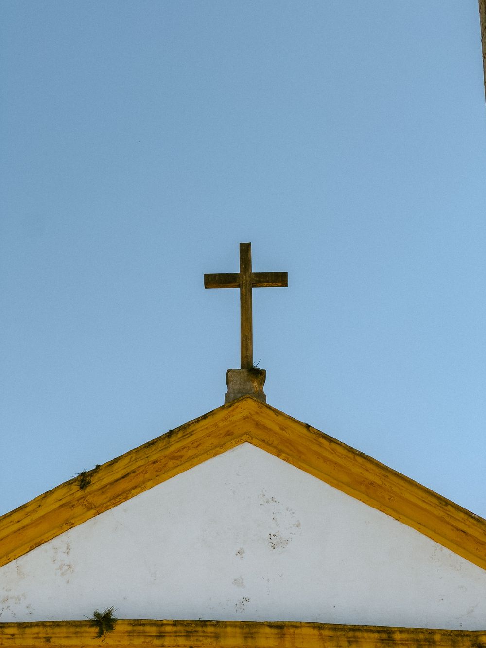 Close-up of a church roof with a cross against a clear blue sky, symbolizing faith and spirituality.