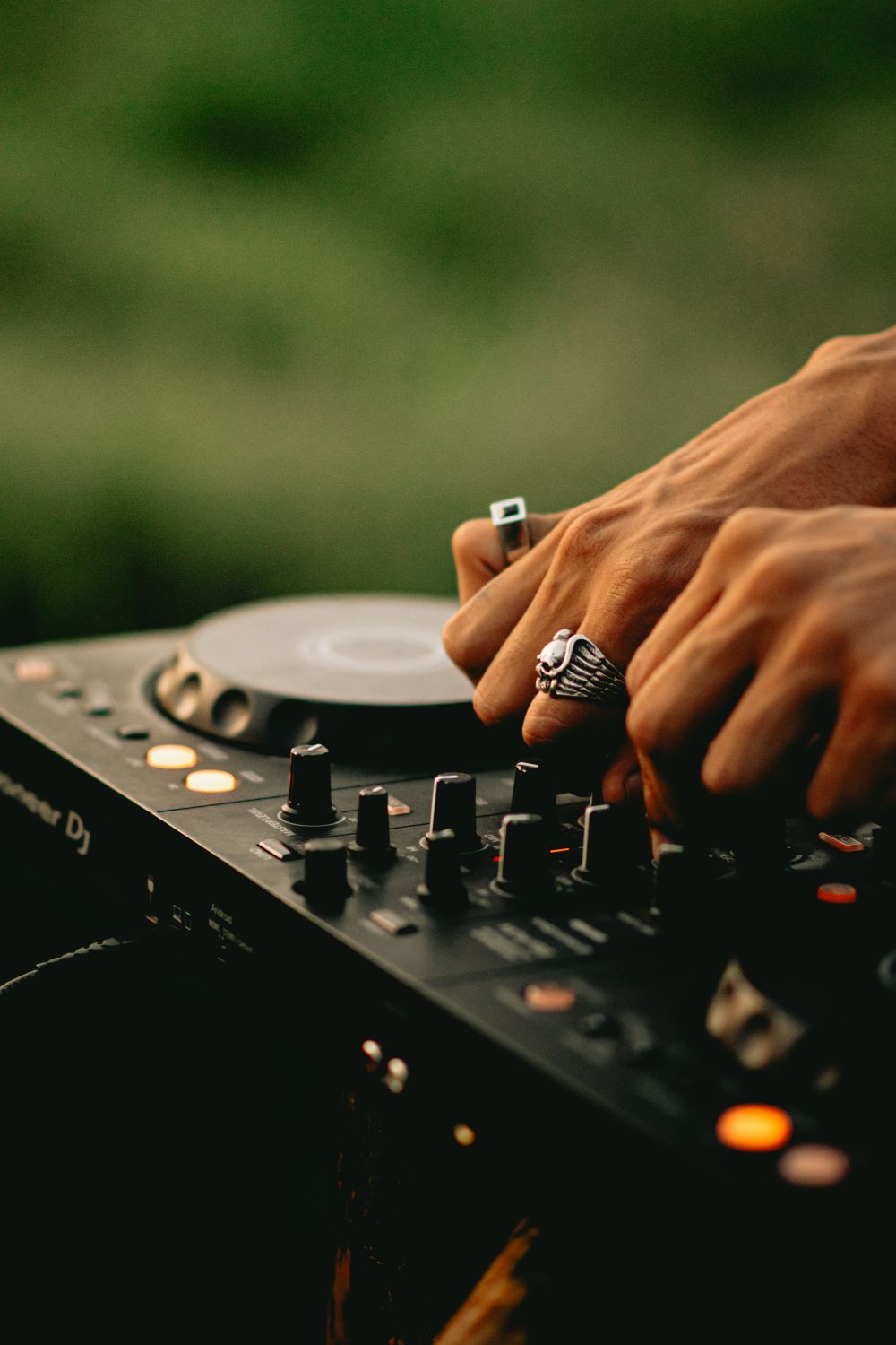 DJ adjusting mixer controls with focused hands, highlighting live music dynamics.