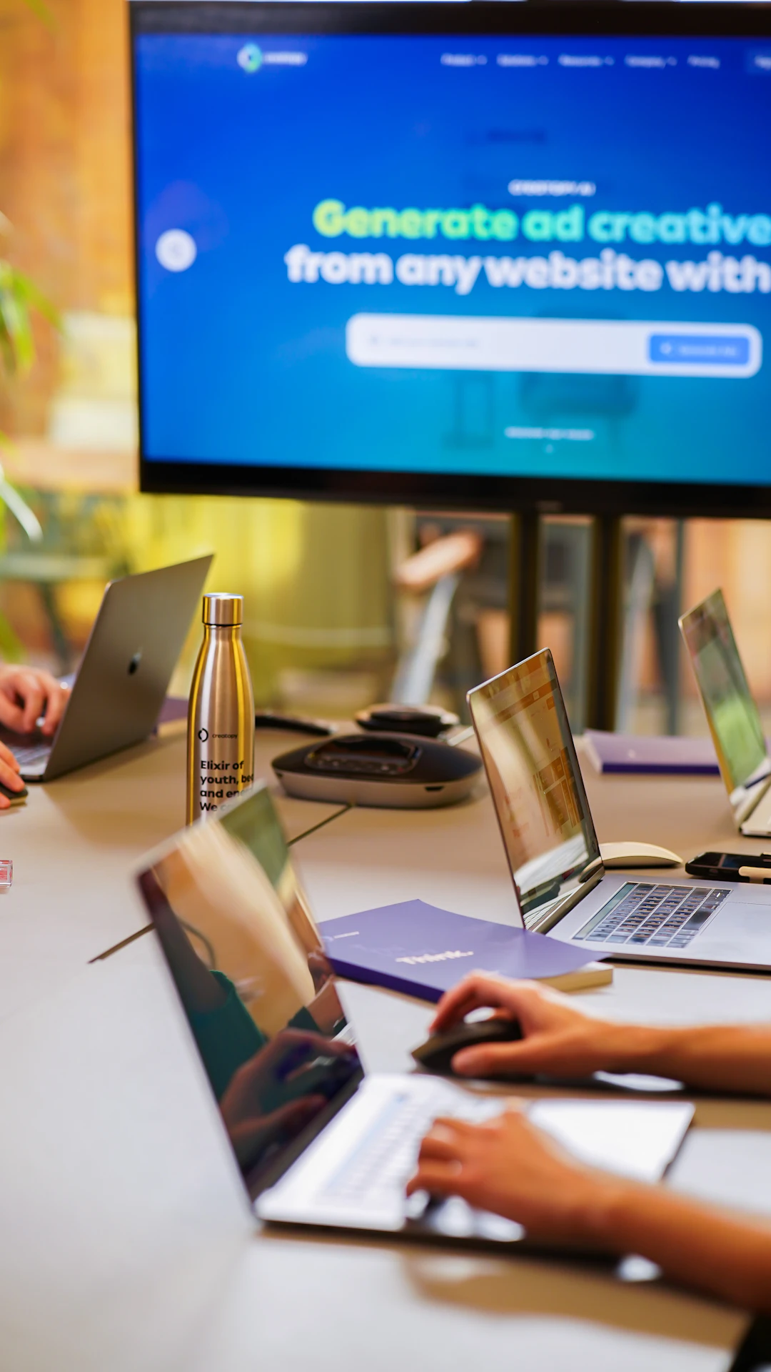 a group of people sitting around a table with laptops