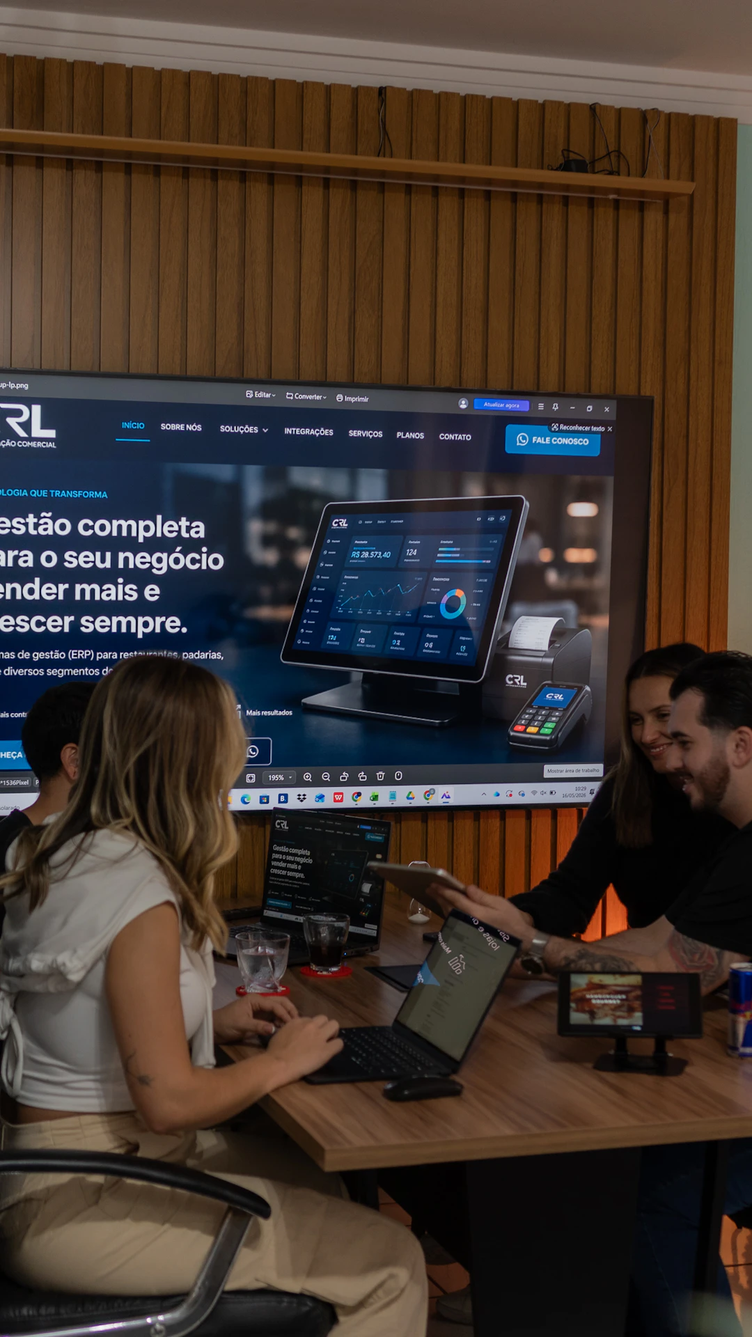 Colleagues collaborating around a table with a large screen display.