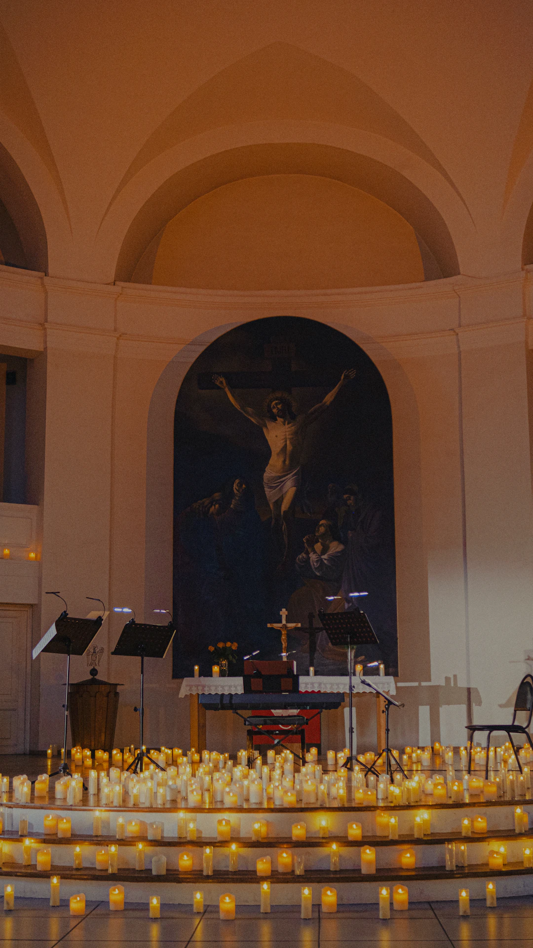 Lit candles illuminate a church altar with a crucifixion painting