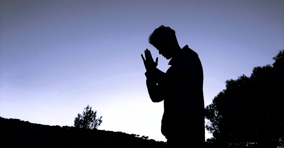a silhouette of a man praying in the evening