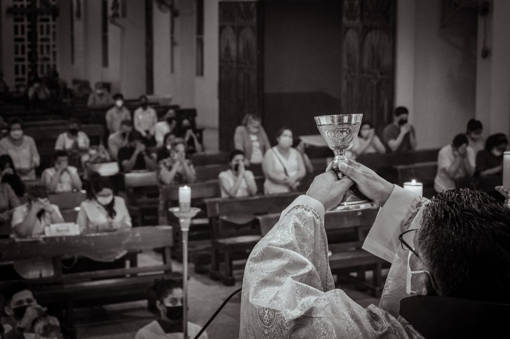 A priest holding a chalice during a church mass with worshippers in Guayaquil, Ecuador.
