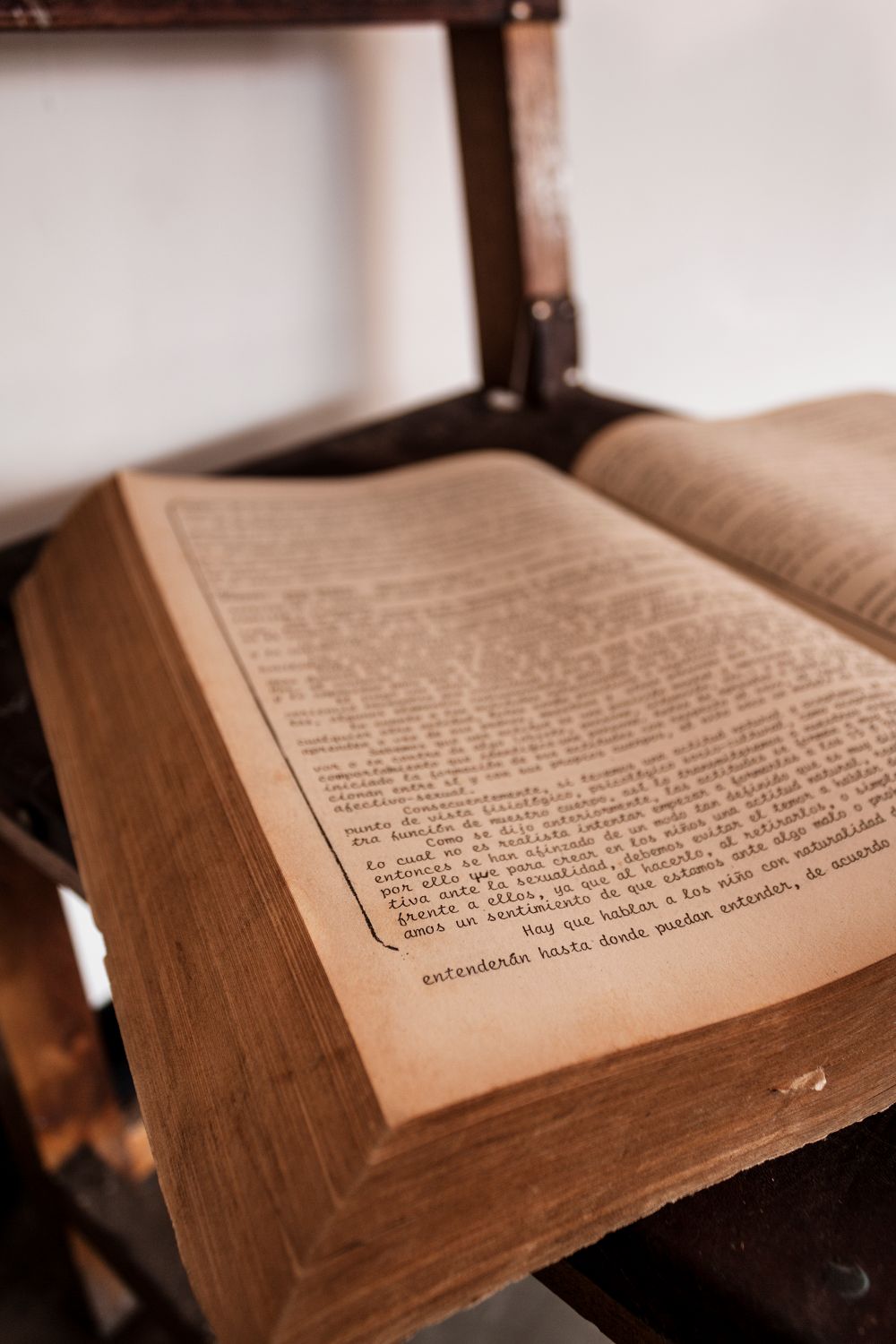 Close-up of a vintage open book on a rustic wooden table, showcasing aged pages and text.