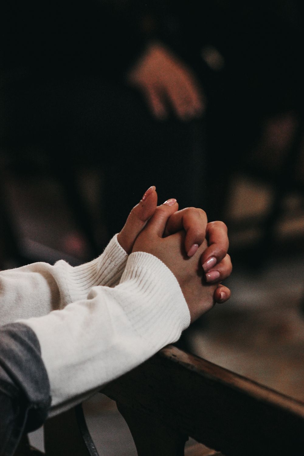 Close-up of hands clasped in prayer, reflecting faith and devotion inside a church.