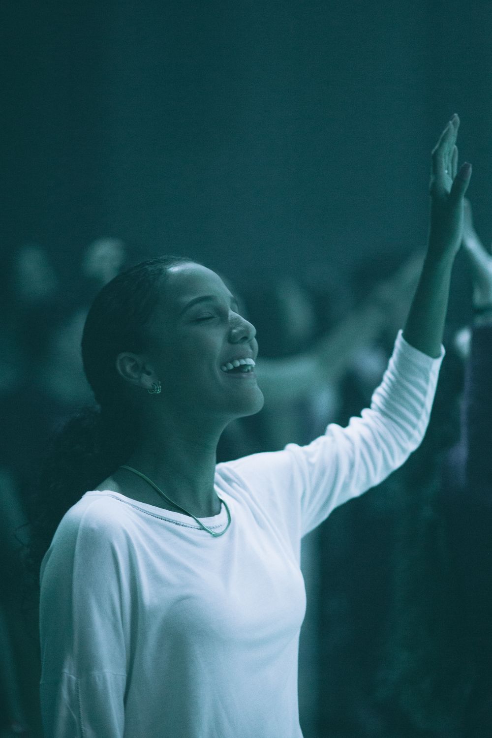 A woman sings passionately during a worship service, surrounded by a congregation.