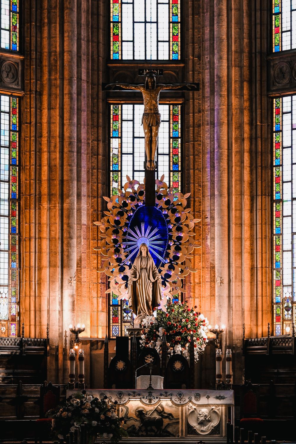 A stunning church interior featuring a crucifix, stained glass windows, and religious statues.