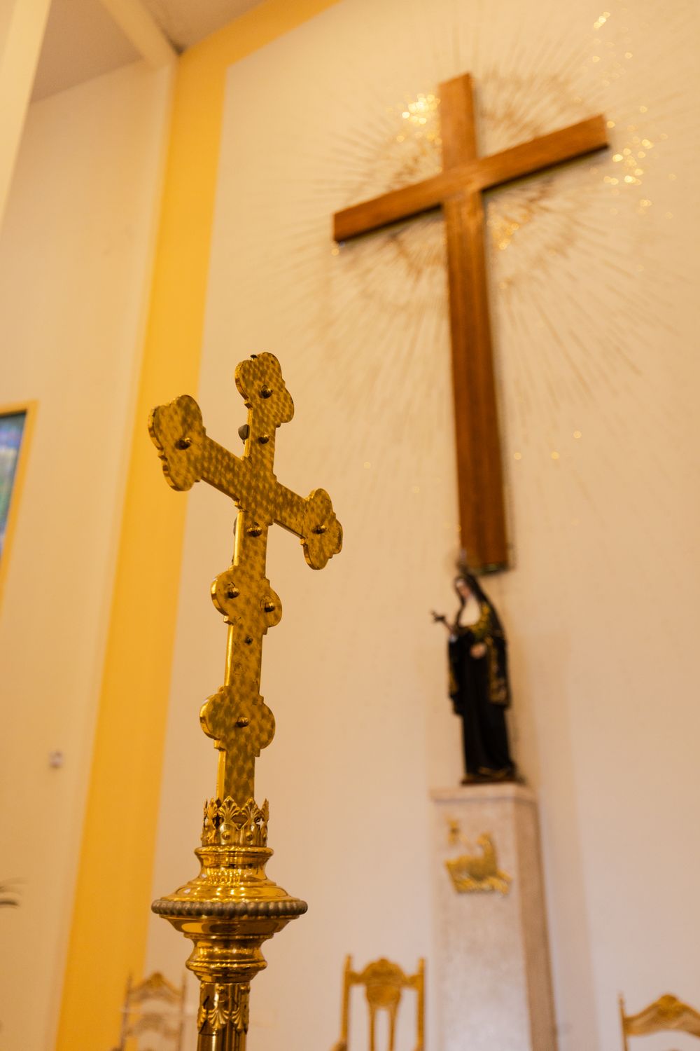 A golden crucifix stands inside a São Paulo church with a prominent wooden cross in the background.