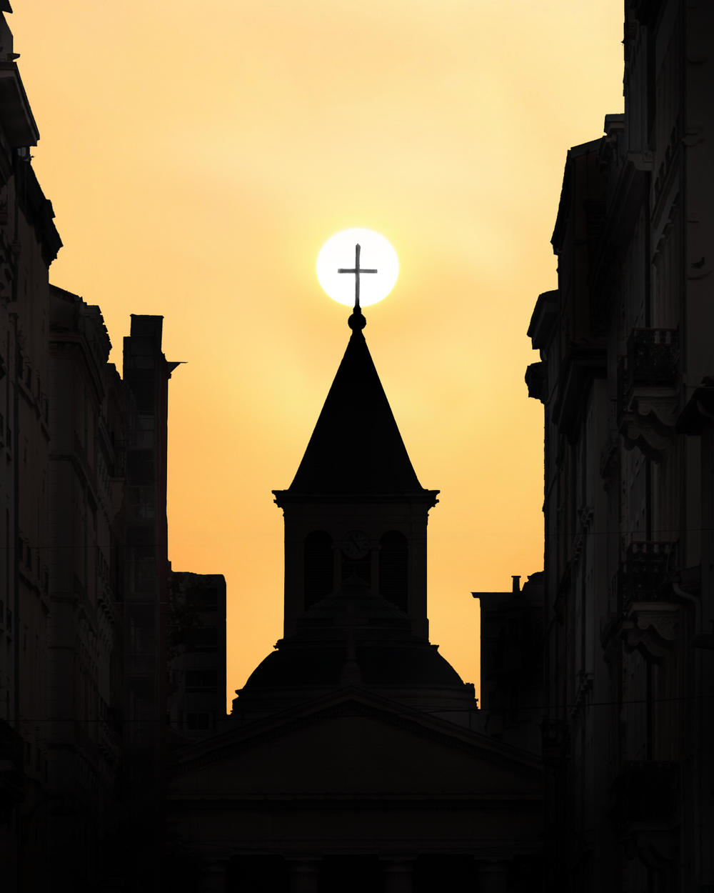 A striking silhouette of a church against a vibrant sunset in Lyon, France.