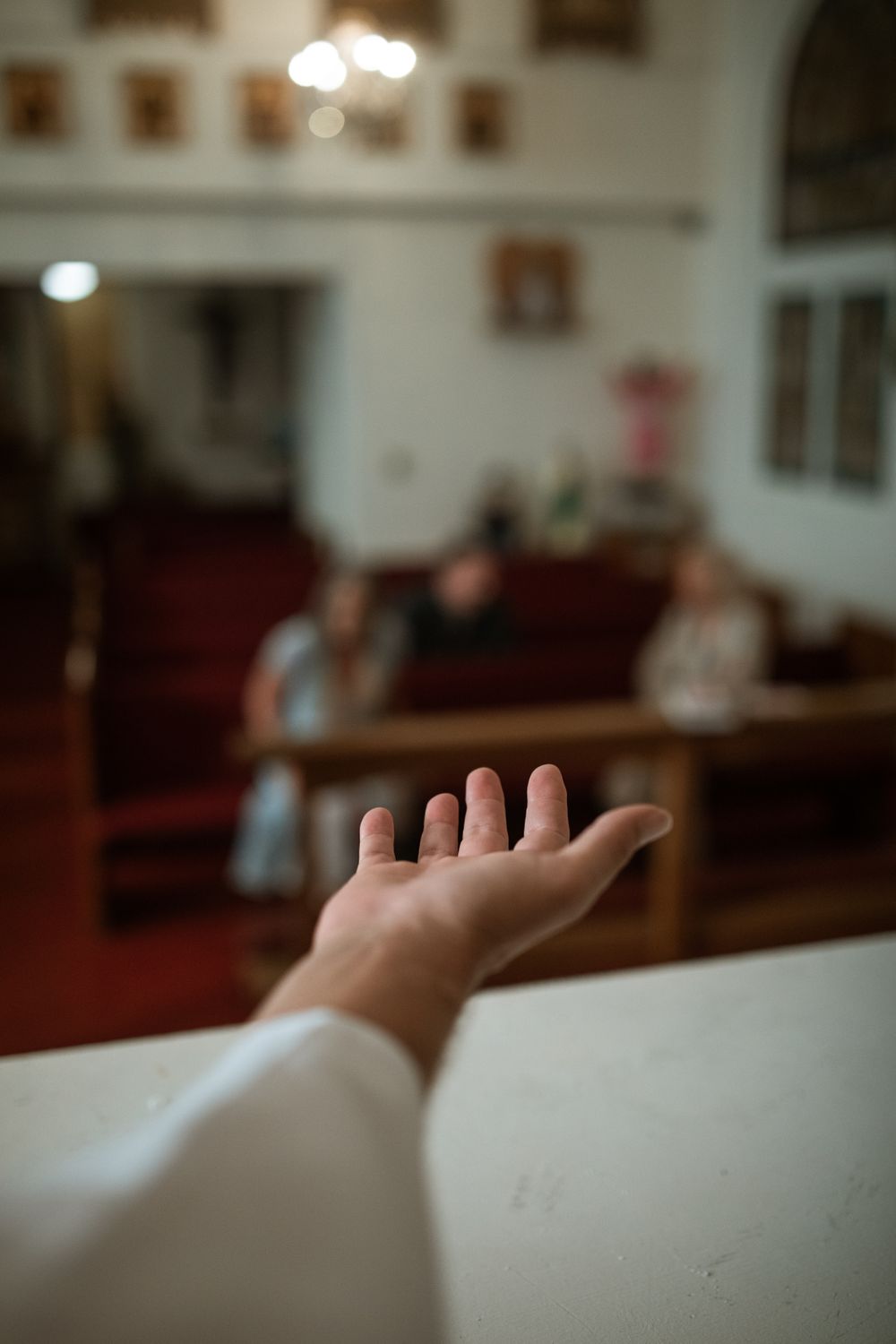 A hand reaching out in a church setting, symbolizing faith and community.