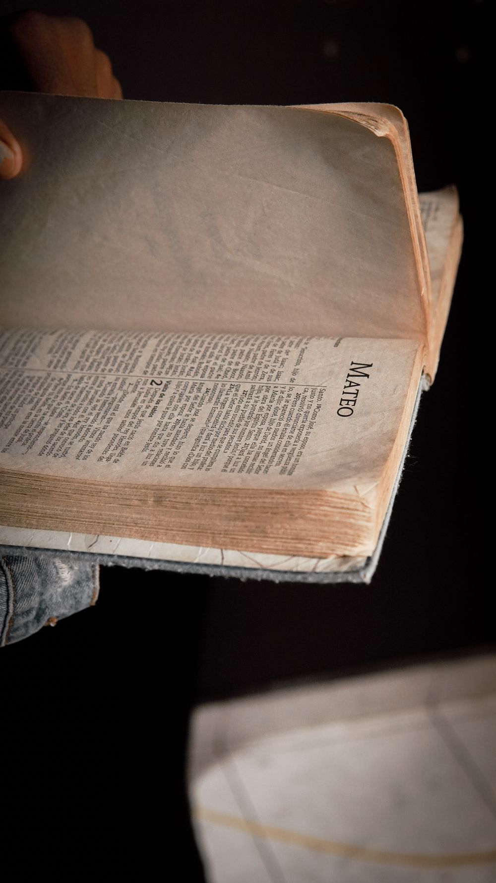 A close-up view of an open Bible, hand turning pages. Focus on the book of Matthew.