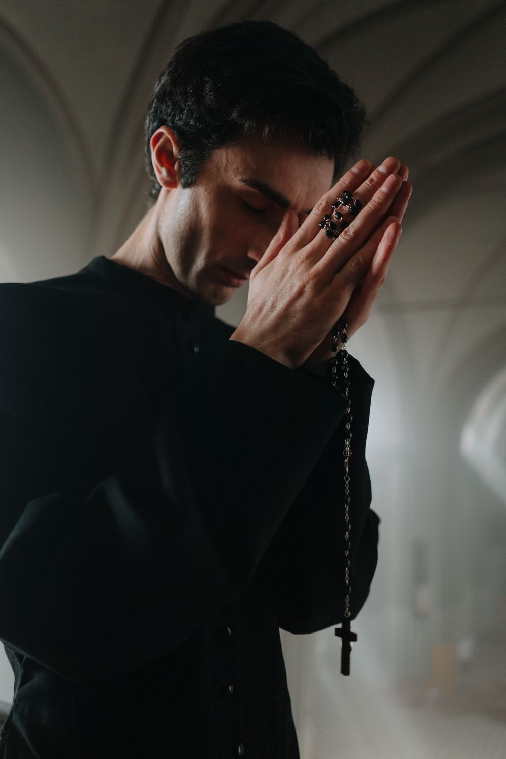 A man in deep prayer, holding a rosary, in a serene church setting.